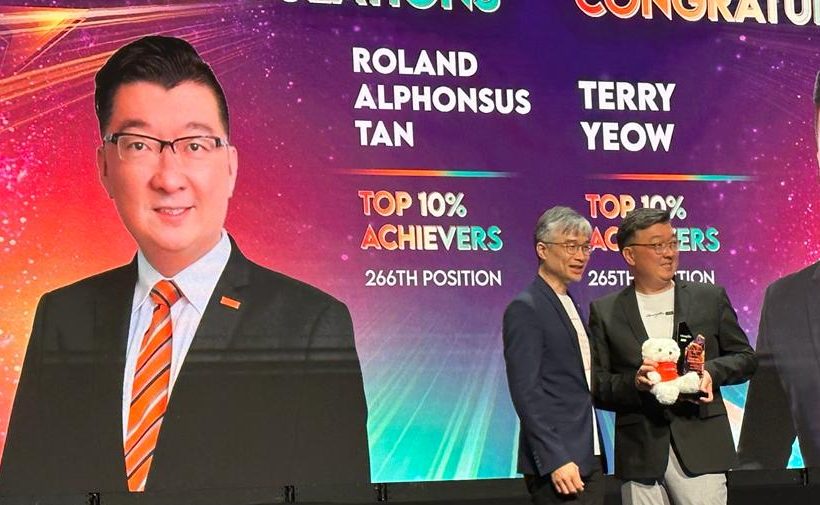 Alphonsus Roland Tan standing on stage at the OrangeTee Annual Achievers Awards 2023, for his achievements as a real estate agent in 2023.